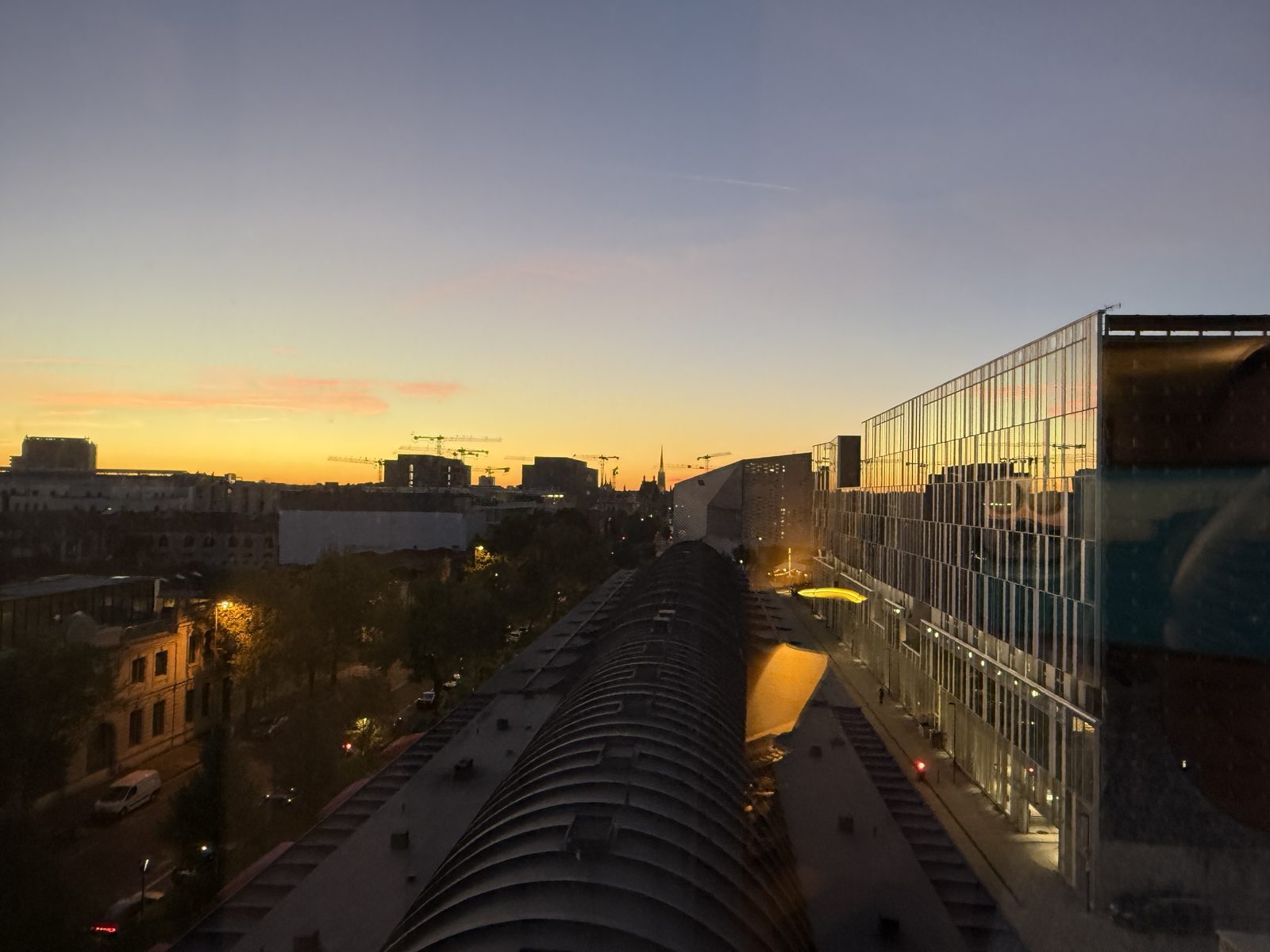 Sunset over the rooftops and cranes of Bordeaux.