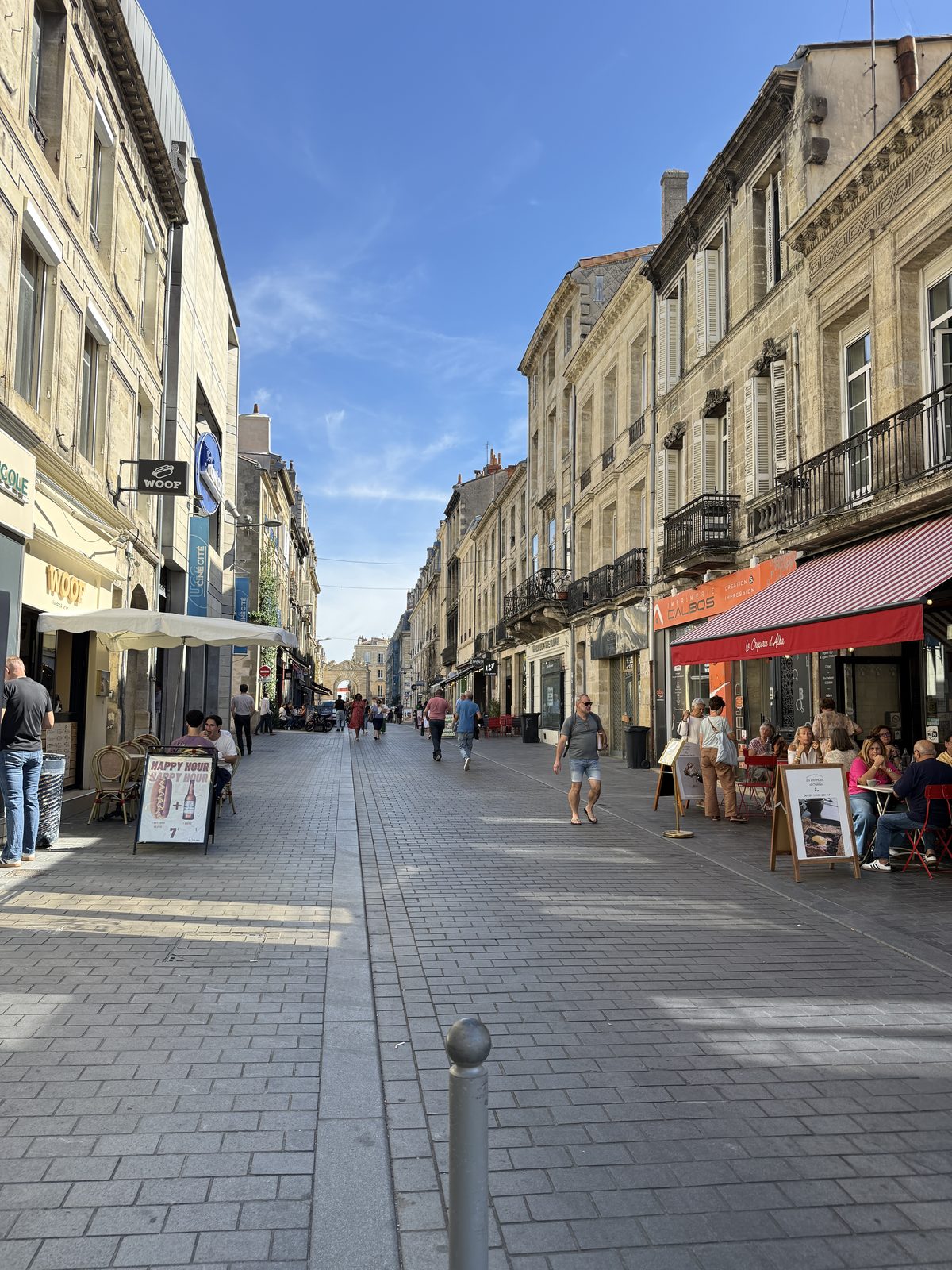 A bustling pedestrian shopping street in the heart of Bordeaux, lined with cafés and historic facades.