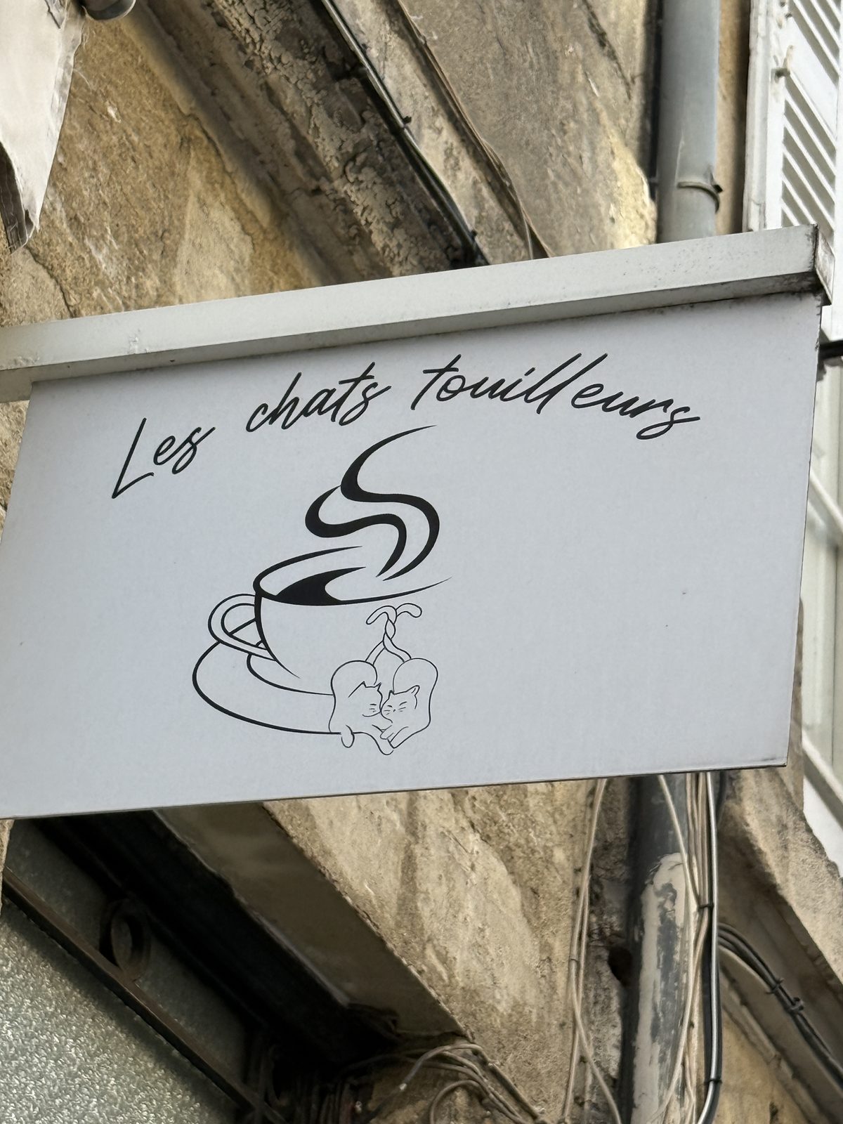 A charming sign for "Les Chats Touilleurs," a cat café.
