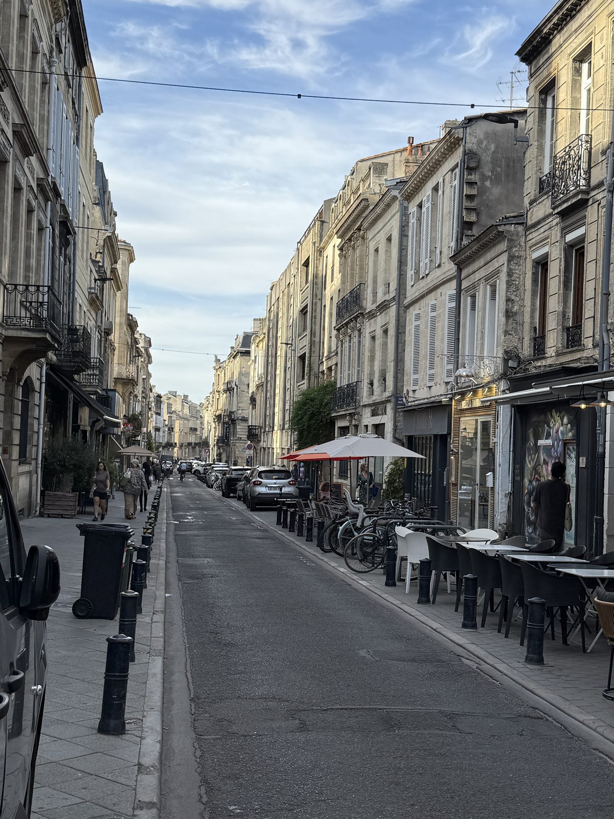 A quiet café-lined street glowing in the early-evening light.