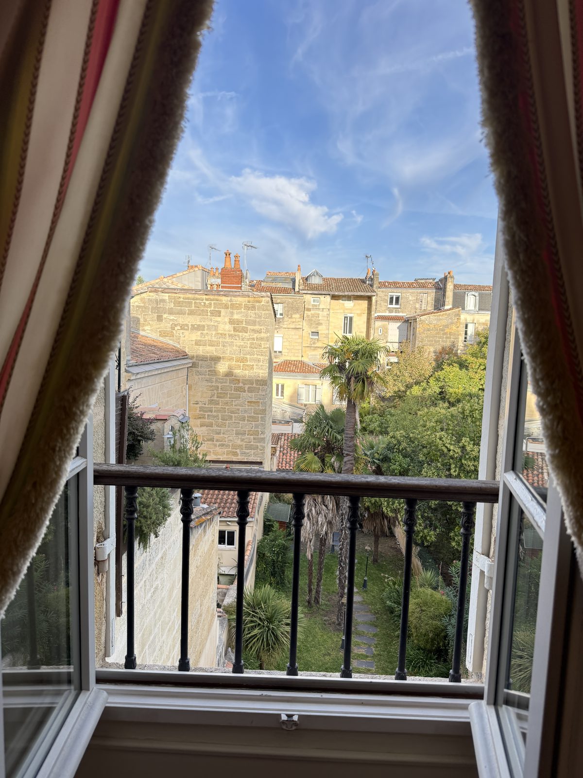 The view from Liz and Beth's room's balcony at Villa Victor Louis, framed by the curtains and looking over the old city rooftops.