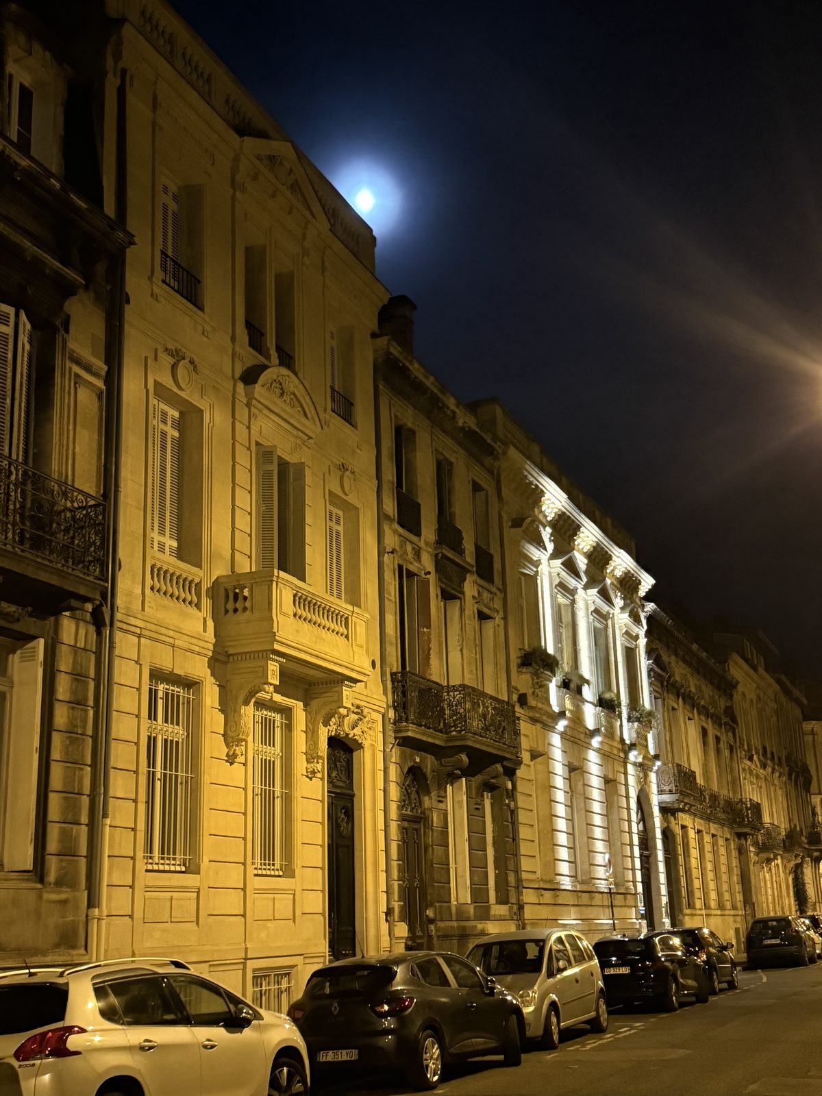 A near-full moon rises over a floodlit Bordeaux street on the walk home after dinner — the perfect end to the day.